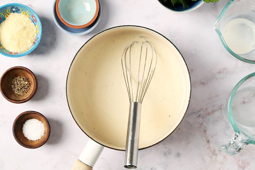 Process of making Taste of Home's Creamed Pearl Onions in a green casserole dish on a grey marble surface.