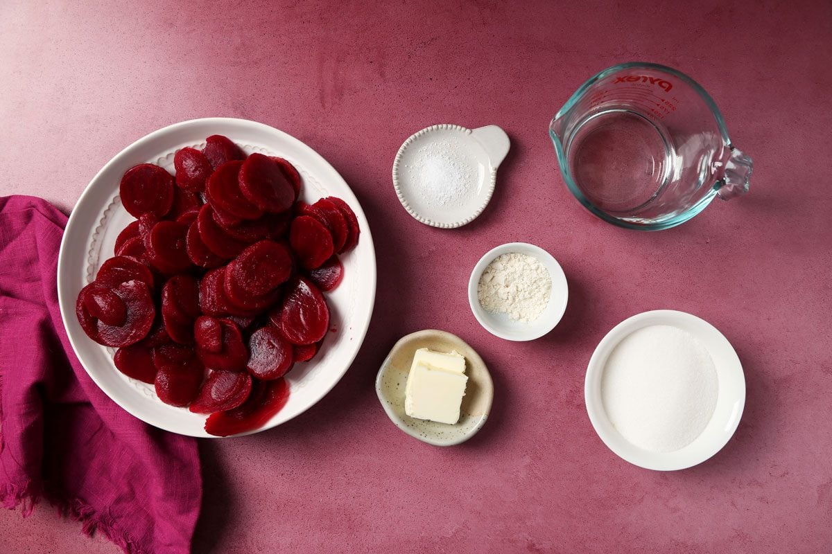 Close up of Taste of Home's Harvard Beets served on white plates on a magenta surface.