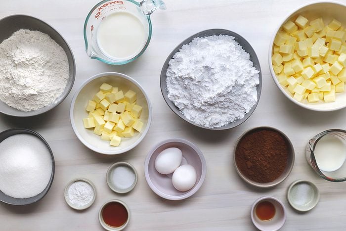 butter, sugar, eggs, vanilla extract, flour, baking powder, salt, milk, confectioners sugar, cocoa in bowls