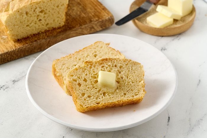 Close-up horizontal shot of the Taste of Home English Muffin Bread, highlighting the grainy cornmeal crust and the bread’s open crumb texture.