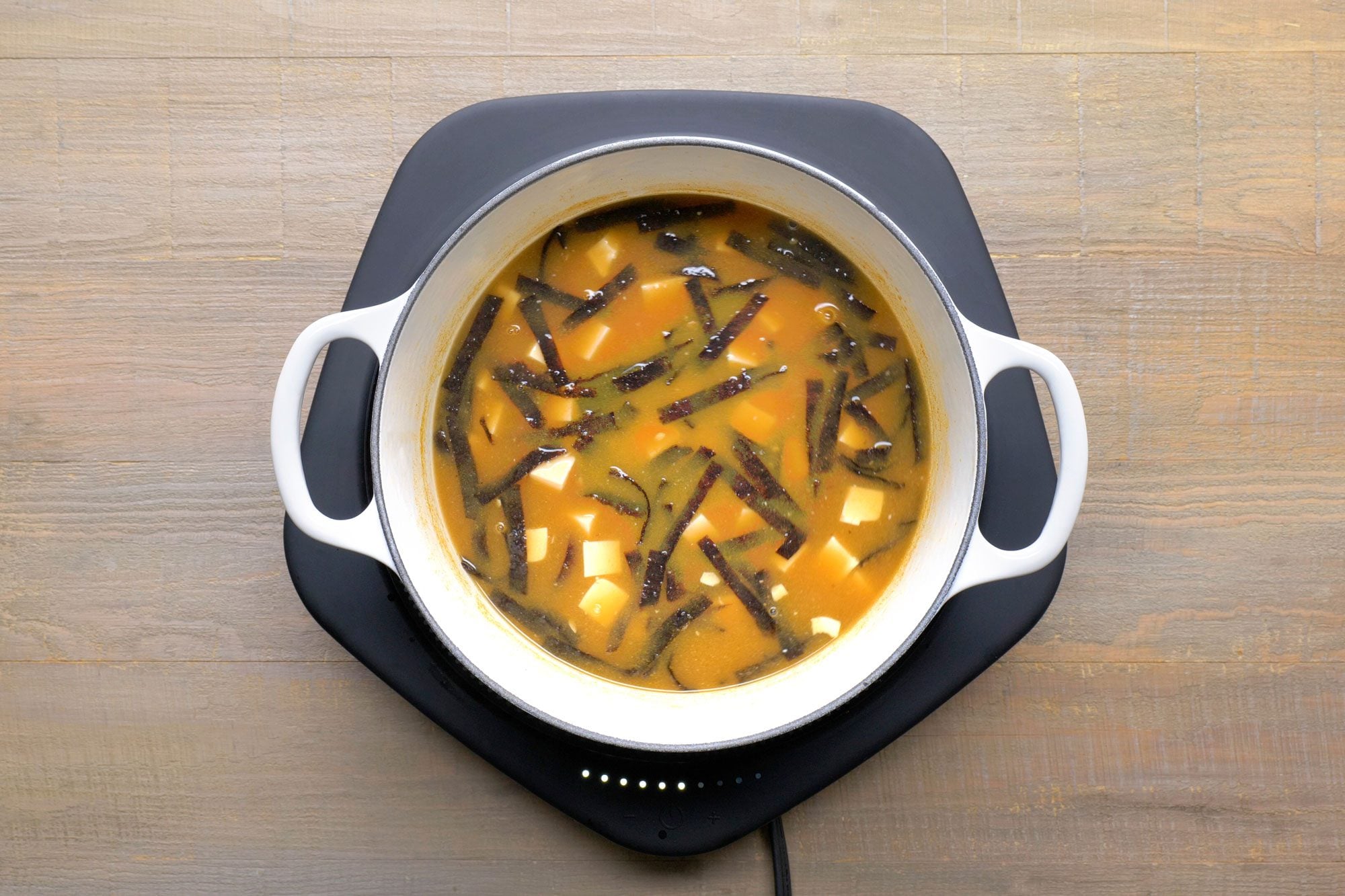 Overhead shot of add soy sauce; induction; wooden surface;
