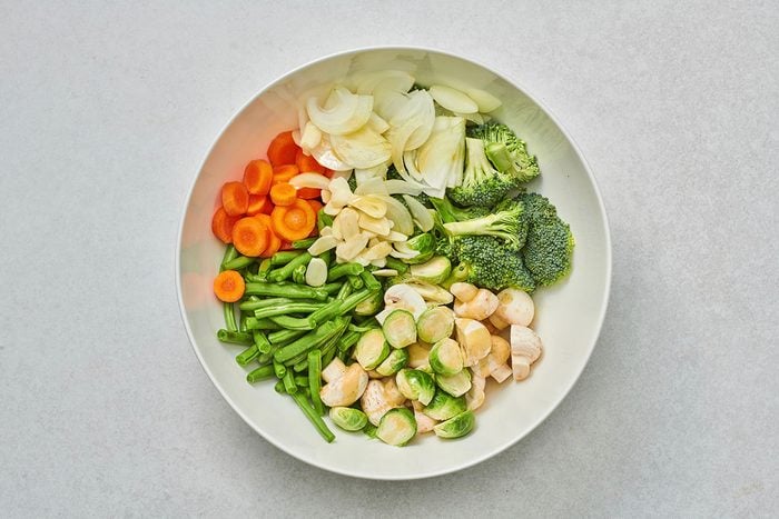 In a large bowl, combined green beans, broccoli, mushrooms, Brussels sprouts, carrots, onion, and garlic