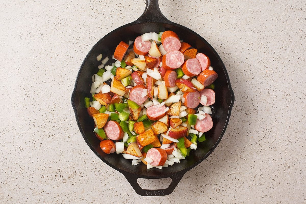 Brats And Potatoes And Veggies Cooking In Skillet