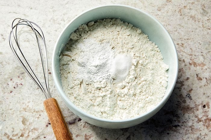 Dry ingredients for lemon olive oil cake in a bowl with a whisker