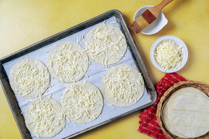tortillas sprinkled with cheese on a tray