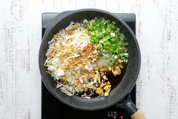 Add the coleslaw mix, green onion, vinegar, sugar, soy sauce, fish sauce, chili garlic sauce, lime juice and peanuts, heat through