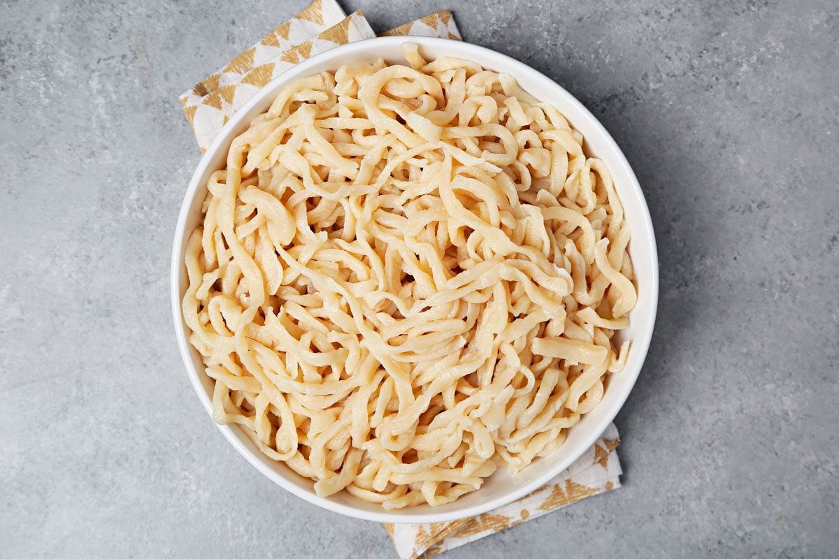 Boiled udon noodles in a large white serving bowl.