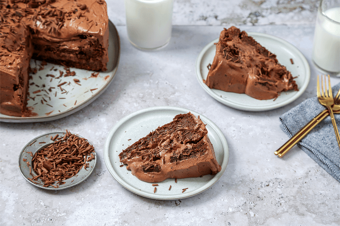 A slice of Brownie Cake served in a plate with gold forks