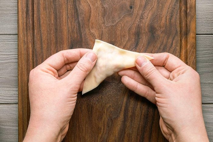 Wonton wrapper being folded in half