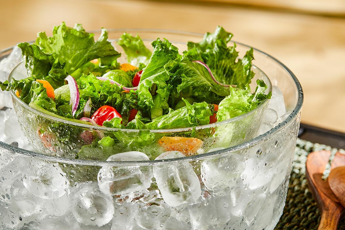 A bowl of vegetable salad placed over a larger bowl filled with ice.