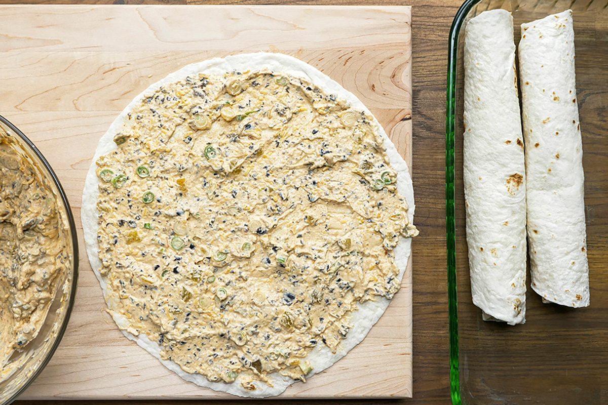 Overhead shot of spread about 1/2 cup on each tortilla; wooden board; wooden surface