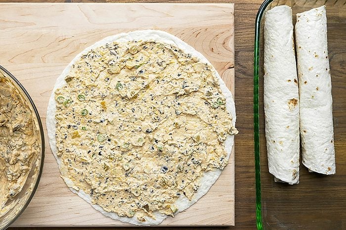 Overhead shot of spread about 1/2 cup on each tortilla; wooden board; wooden surface