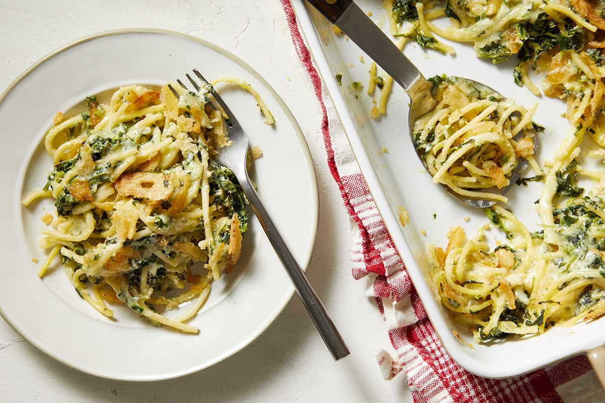 Overhead shot of Monterey Spaghetti; in a baking pan with serving spoon on a napkin; served spaghetti on a white plate with a fork;