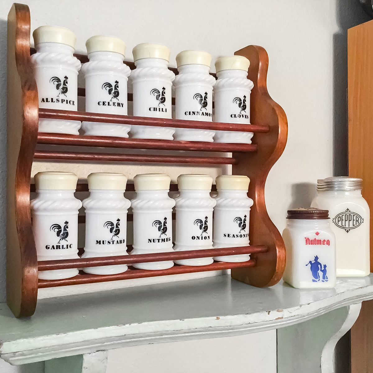 A wooden spice rack holds ten white spice jars with black labels. Two larger white jars labeled "Talcum" and "Superfine" sit on the counter to the right of the rack.