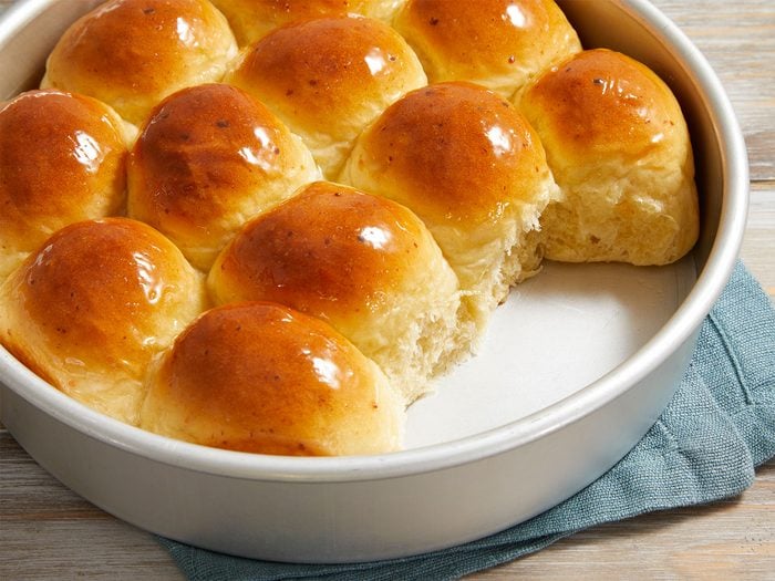 Dinner Rolls In A white Round Pan blue cloth under the pan