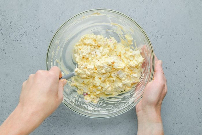 Overhead shot of a small bowl containing the first six ingredients; eggs are added and gently stirred to combine; all set on a grey surface