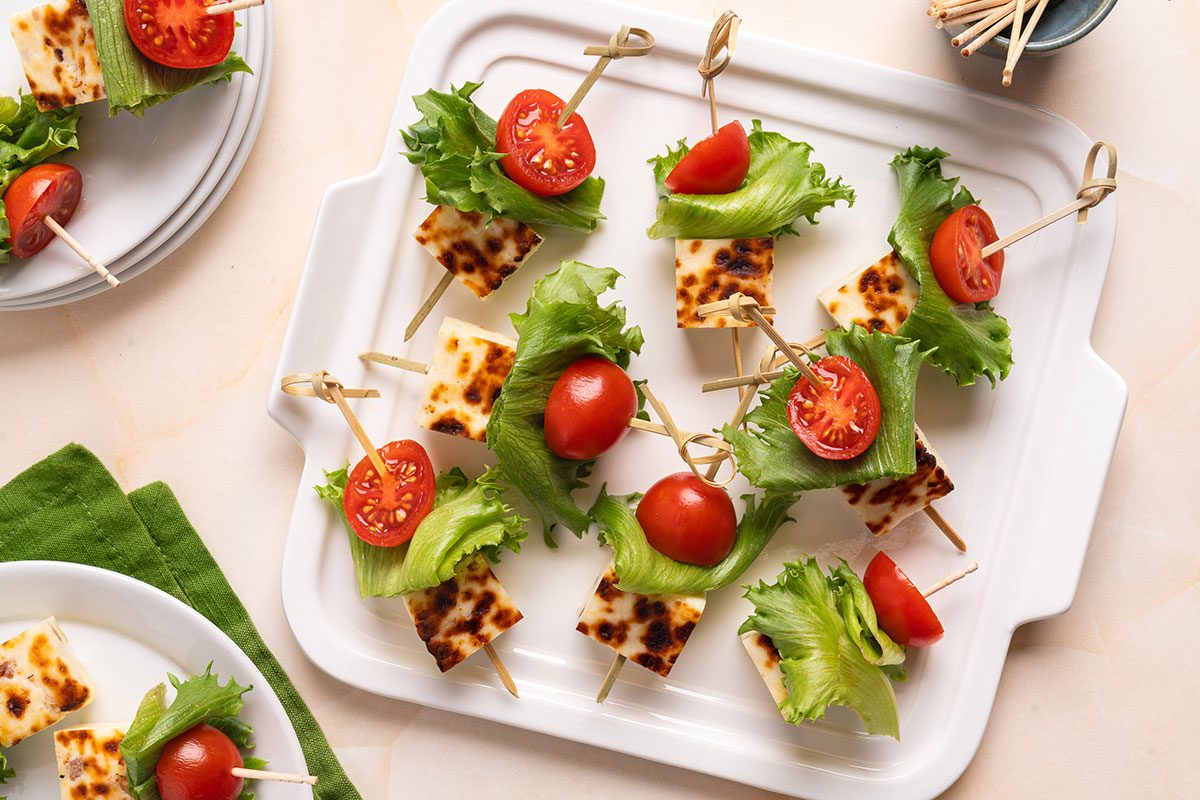 Using an appetizer skewer or toothpick thread a tomato slice, a piece of lettuce, and a cube of cheese on each.