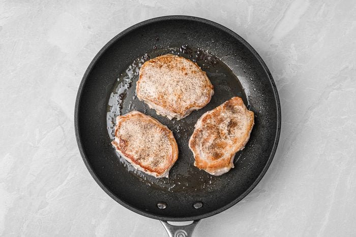 searing pork chops in a skillet