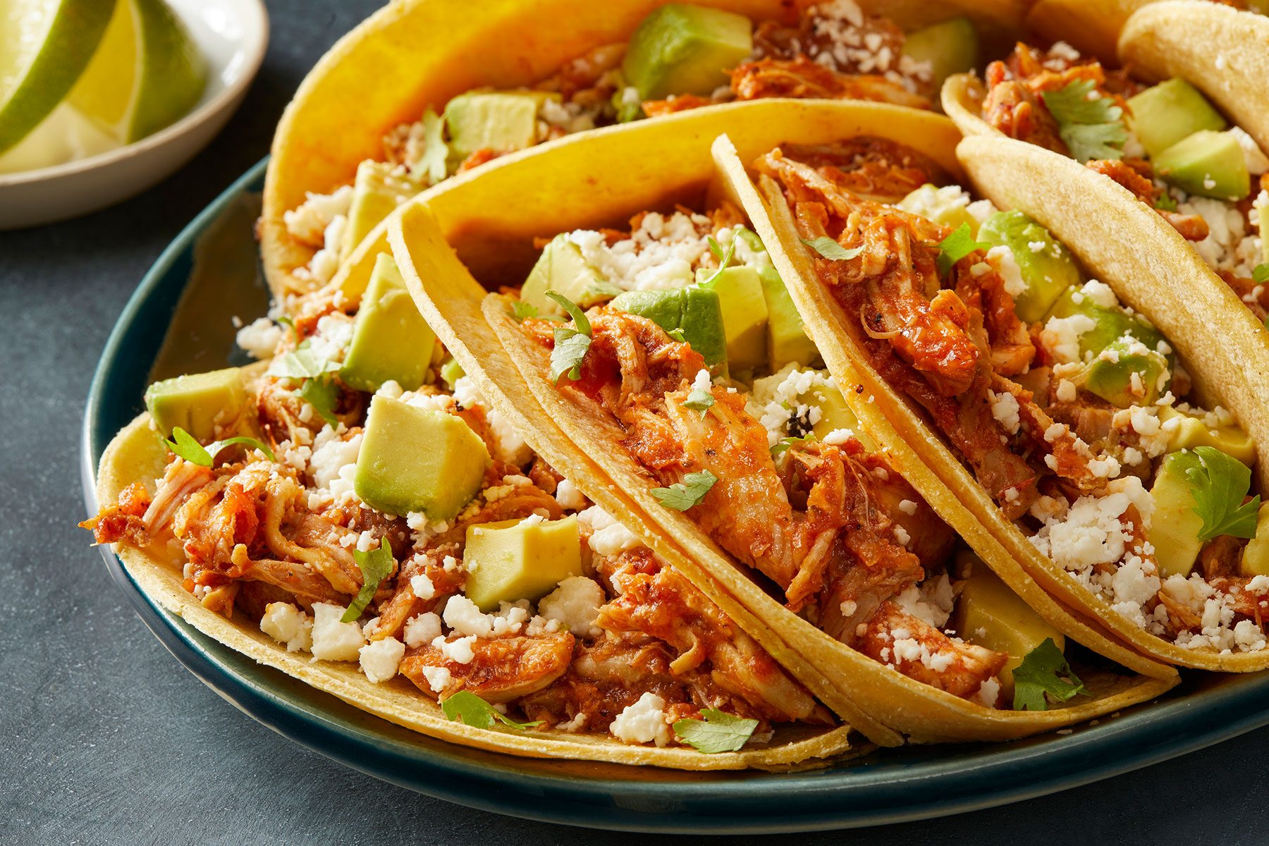 Served the chicken in corn tortillas, and drizzled with sauce. Chicken Tinga Tacos in a plate.