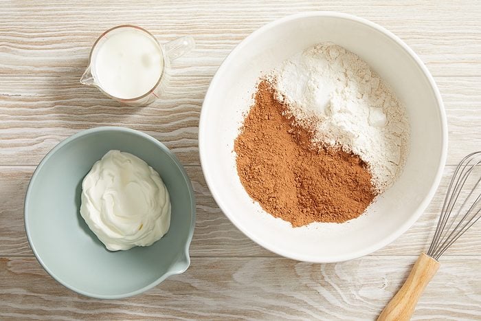 buttermilk in the corner. sour cream in a bowl next to a bowl with flour and cocoa