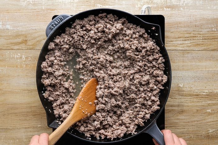 Cooking ground pork, garlic, cloves, nutmeg and cayenne pepper over medium heat in a large skillet.