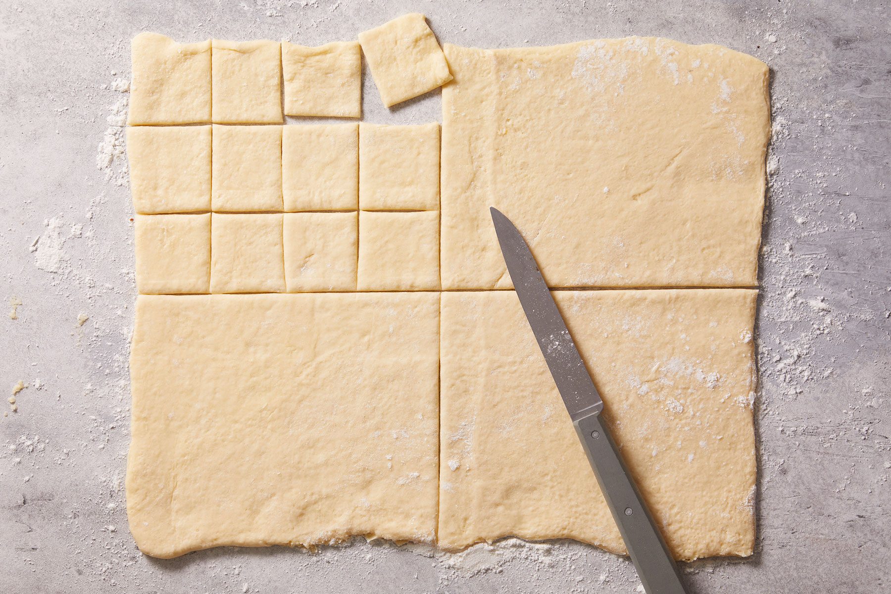 Unrolling the dough into one long rectangular sheet and cut into small square pieces.