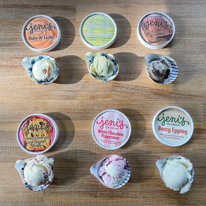 Nine scoops of ice cream on a wooden surface, each paired with a Jeni