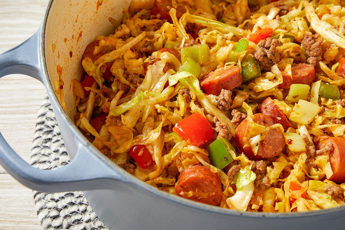 Overhead trend food photography close-up of Dirty Cabbage highlighting sausage slices, tender cabbage, and seasoned vegetables.