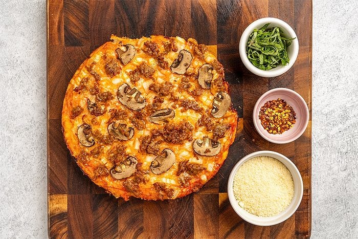 baked dutch oven pizza on a wooden board; seasonings