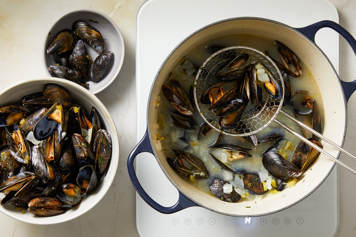 removing mussels with a slotted spoon