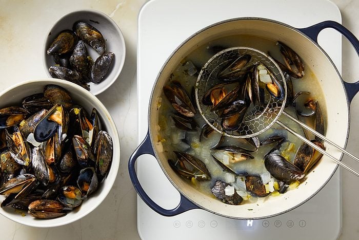 removing mussels with a slotted spoon