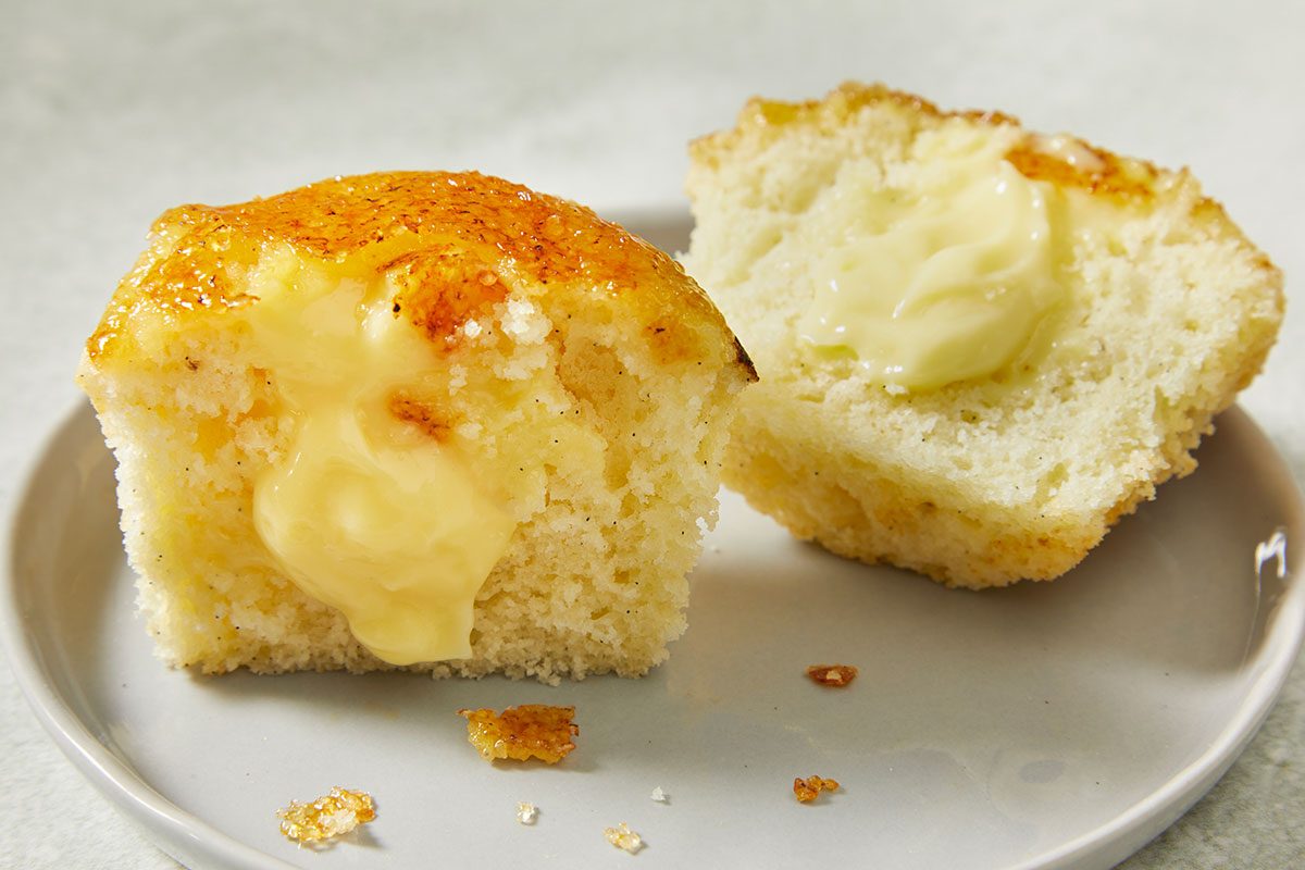 Overhead close-up of a Creme Brulee Cupcake split open to reveal smooth pastry cream filling beneath the crisp caramelized sugar topping.