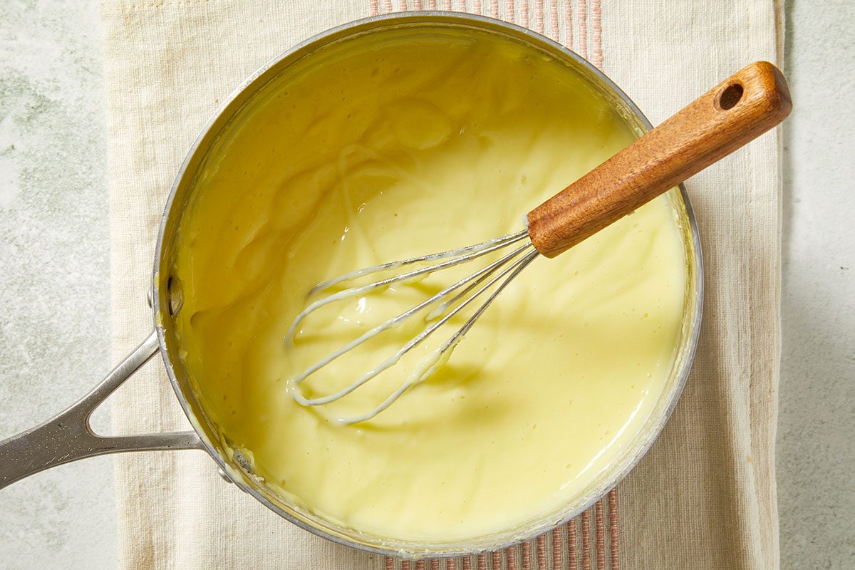 Overhead image of thickened pastry cream cooking in a saucepan with butter and vanilla extract stirred in for a smooth, creamy filling.