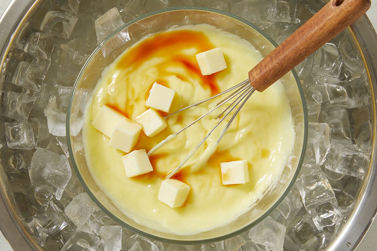 Overhead shot of pastry cream set over an ice bath with cubed butter melting in, cooling the custard quickly to maintain a silky texture.