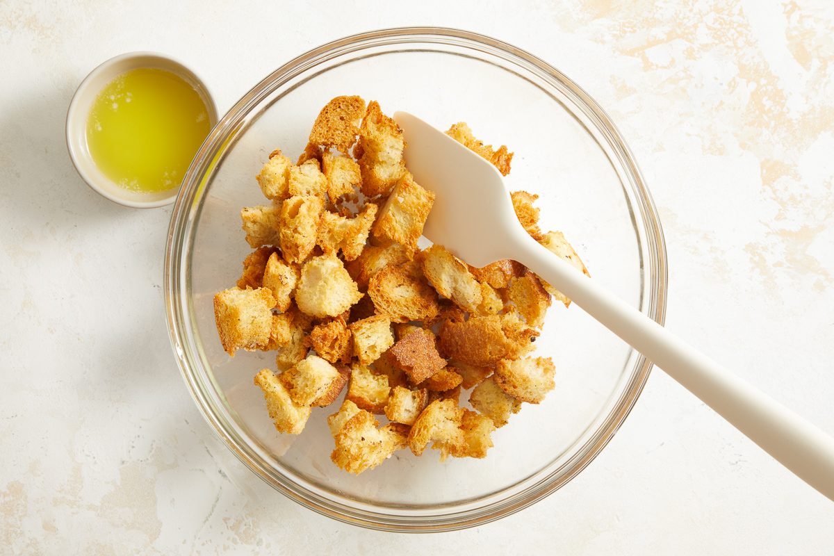 coating croutons with butter in a bowl