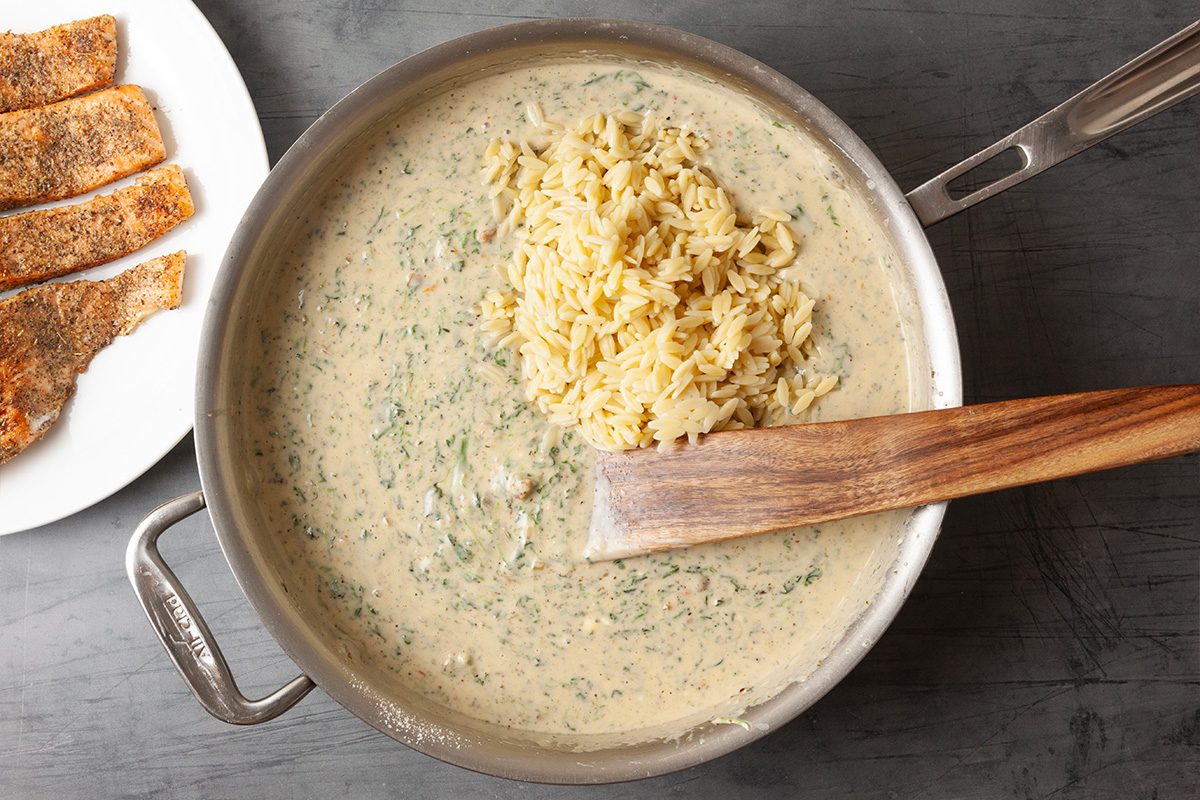 Overhead image of the finished creamy sauce being stirred smooth in the skillet. The sauce appears thick and well blended, ready for the salmon to be returned to the pan.
