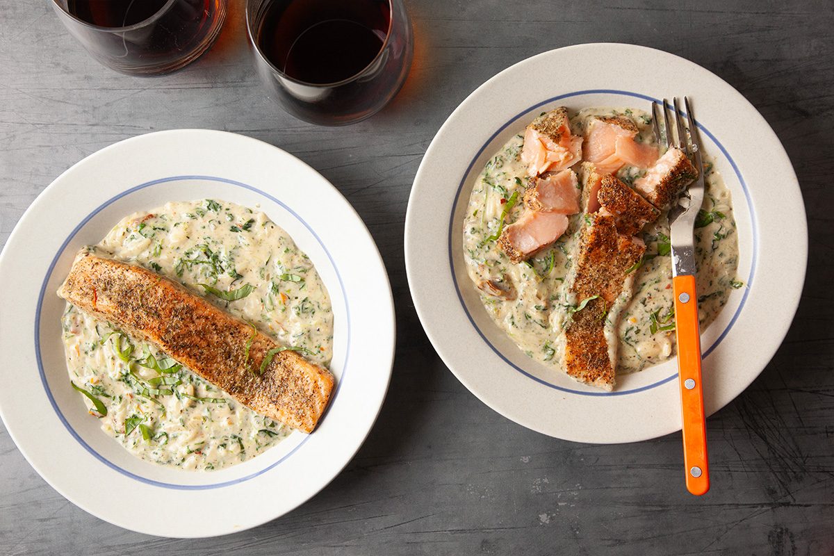 Overhead view of partially eaten plates of Marry Me Salmon with orzo. Forks rest on the plates, emphasizing texture and serving experience.