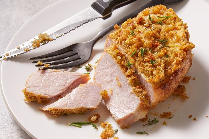 Overhead close-up food photography of sliced Dijon Pork Chop revealing a juicy interior and seasoned bread crumb topping.