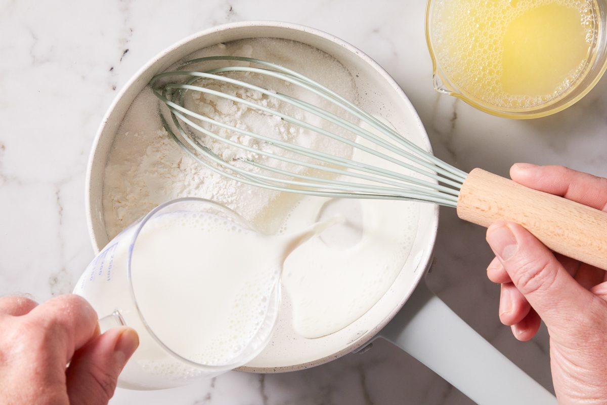 milk being added to sugar and cornstarch mixture