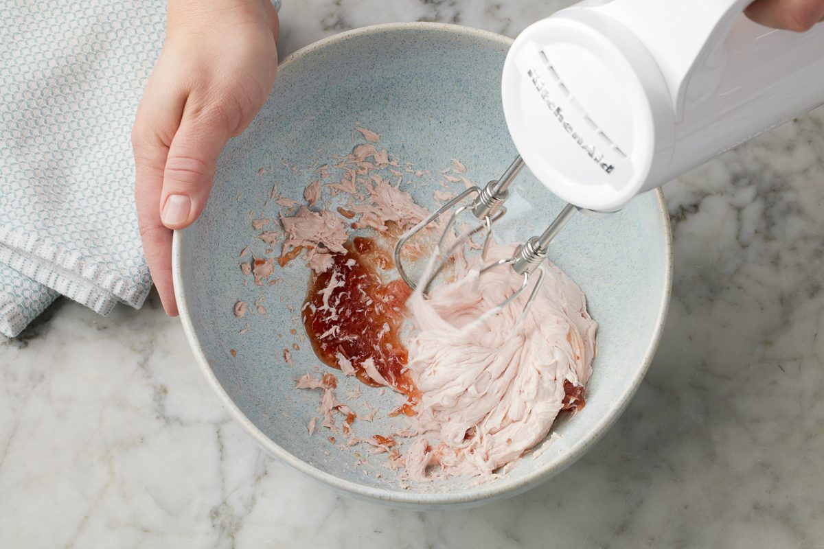 beating cream cheese and strawberry preserves in a bowl