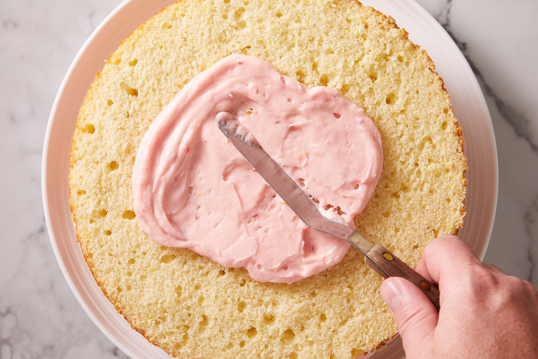 Putting one cup of frosting on a freshly cut cake on a serving plate.