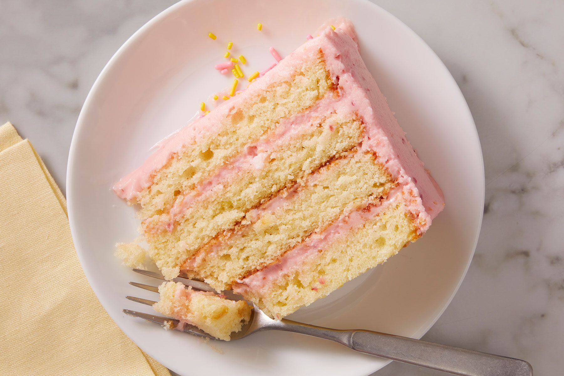 Strawberry Lemonade Cake slice on a white plate with a fork.
