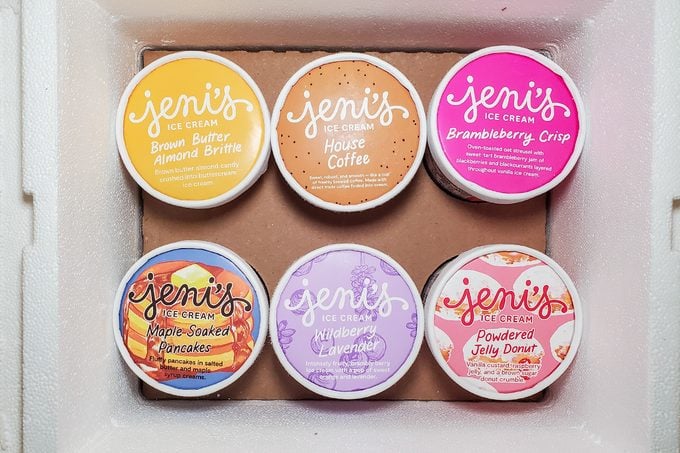 Six tubs of Jeni’s ice cream in a box, each with colorful lids showing different flavors: Brown Butter Almond Brittle, Salted Peanut Butter, Brambleberry Crisp, Cheesecake, Wildberry Lavender, and Strawberry.