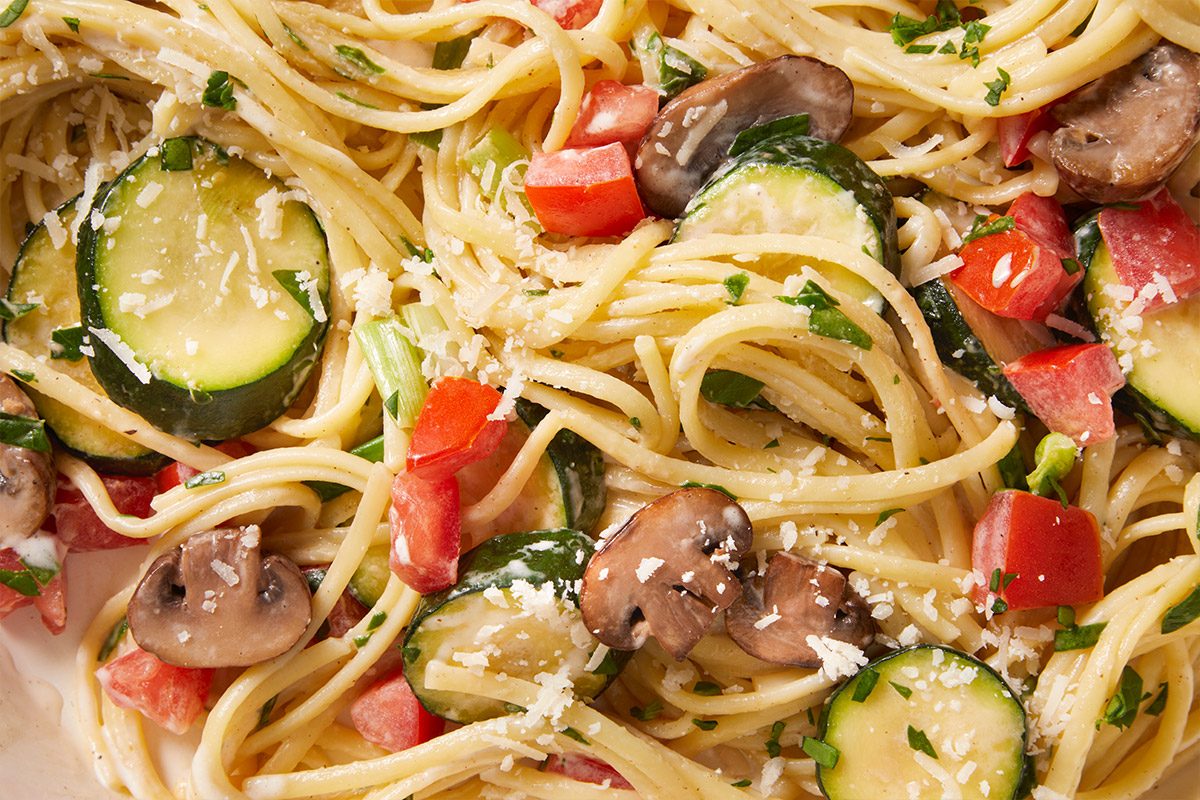 Close up shot of a pan filled with Vegetable Linguine mixed with sautéed zucchini, mushrooms, and tomatoes