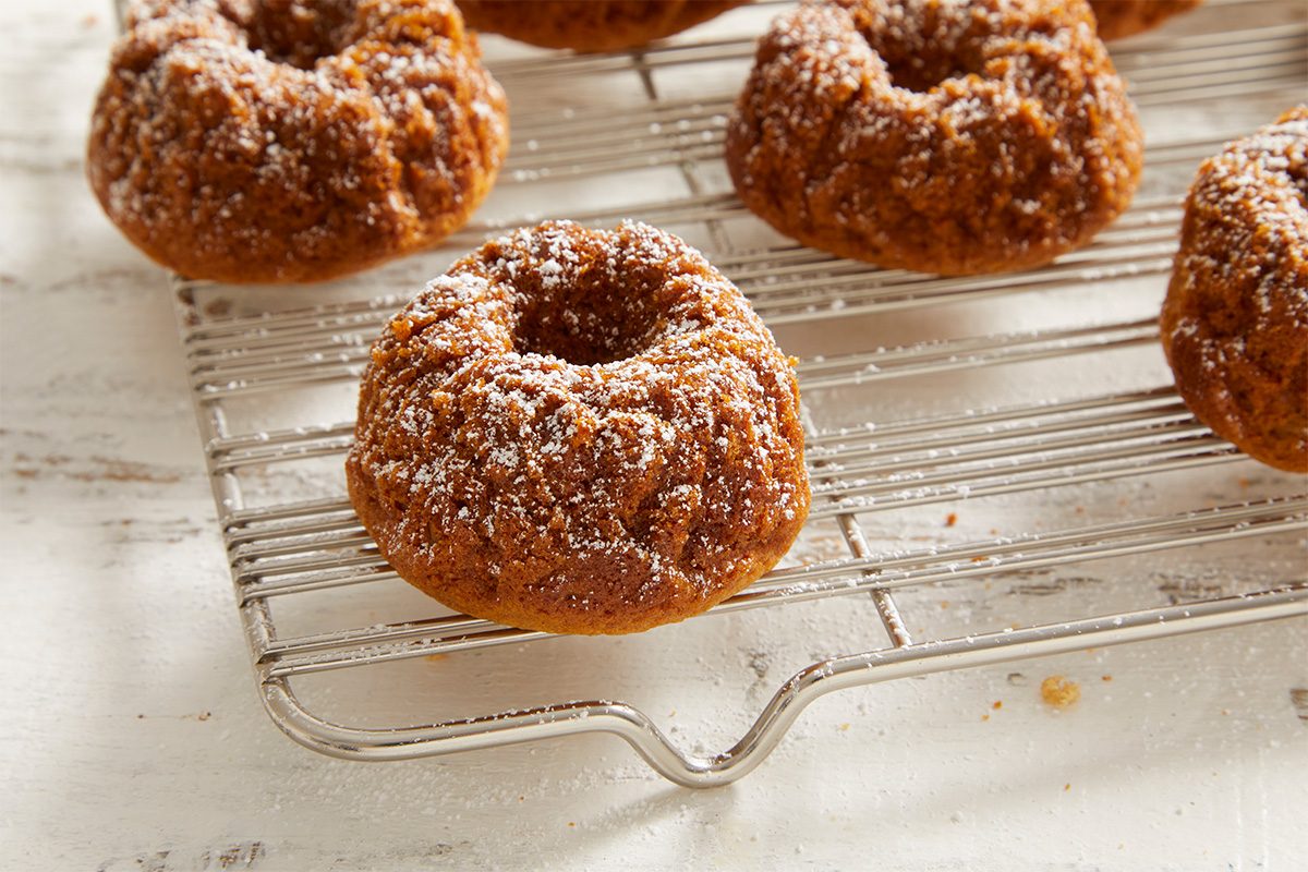 3/4 shot of Baked Doughnuts cooling on a wire rack, coated with cinnamon sugar.