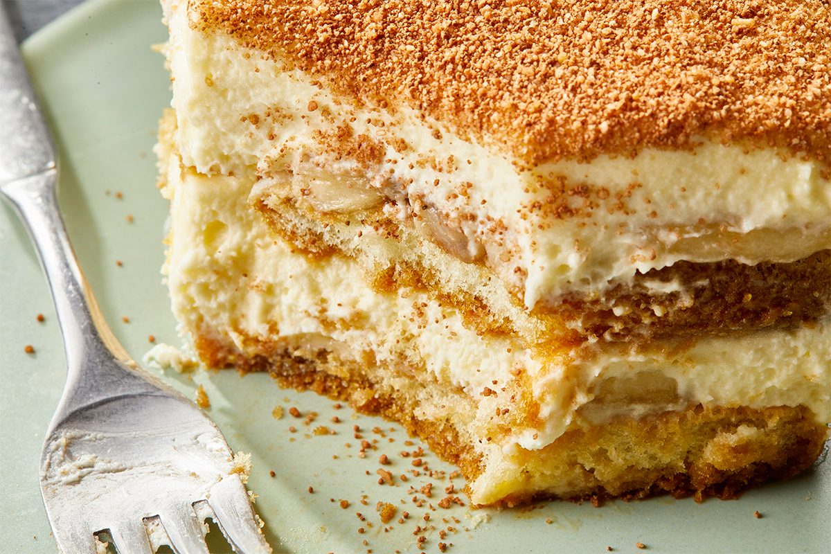 Overhead close-up of Banana Pudding Tiramisu highlighting detailed layers of ladyfingers, banana slices, and mascarpone filling beneath a cocoa-dusted surface.