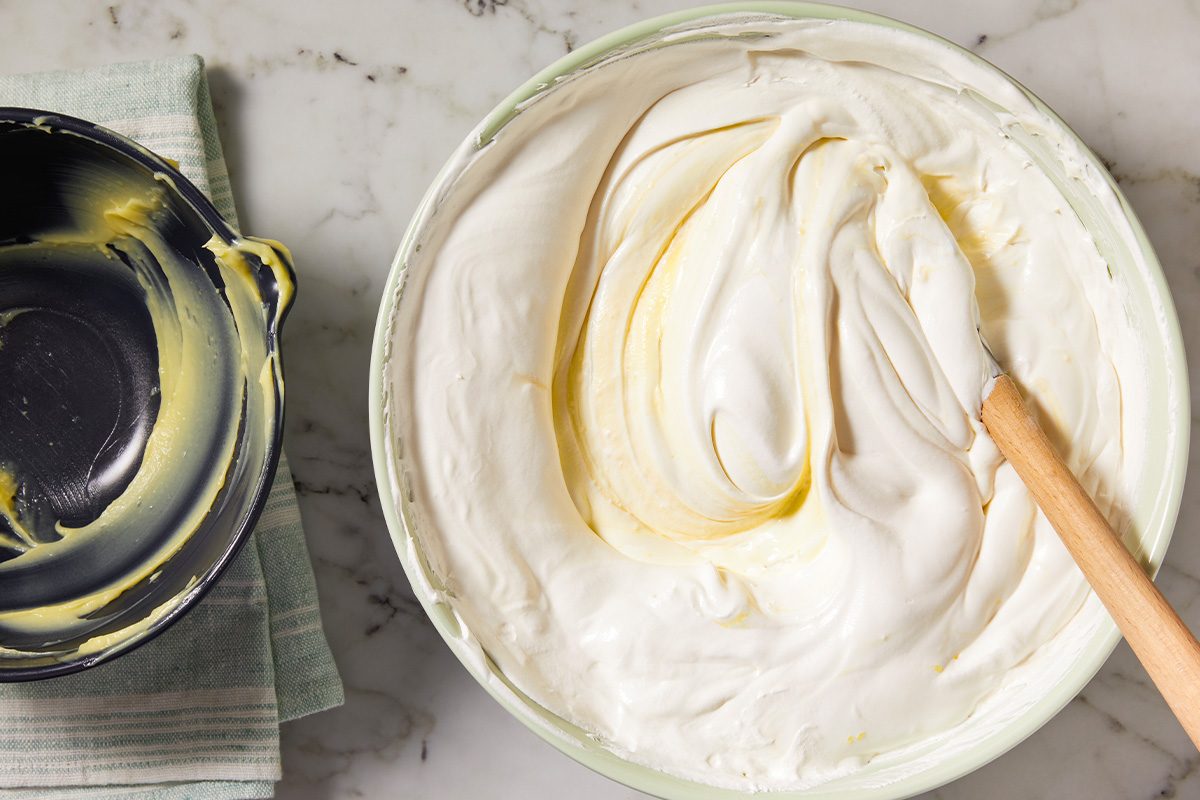 Overhead horizontal image of whipped topping being folded into pudding mixture to create a creamy filling.