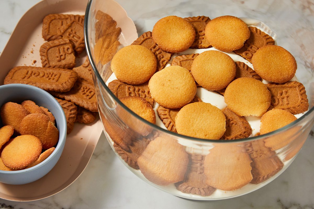 Overhead horizontal image of vanilla wafers and Biscoff cookies layered in a glass bowl.