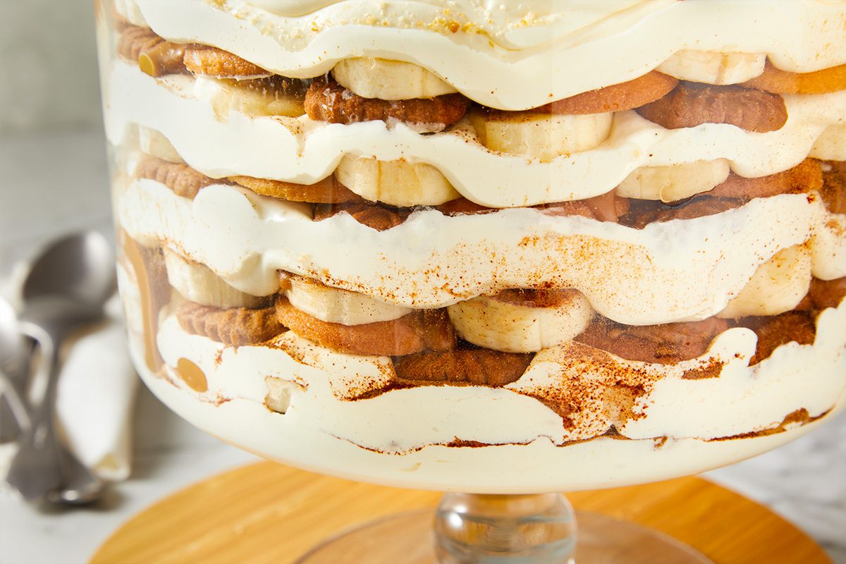Eye-level horizontal close-up of layered banana pudding showing alternating layers of cookies, cream, and bananas.