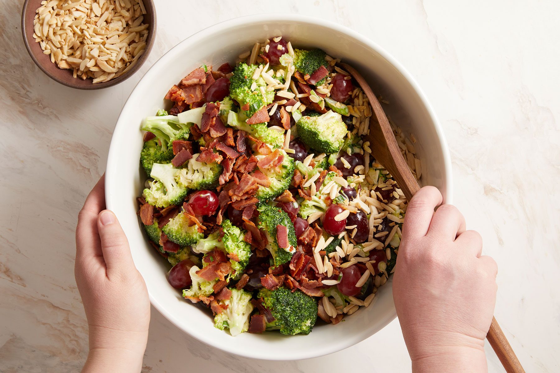 Gently stirring in the bacon and almonds to the Broccoli Grape Salad.